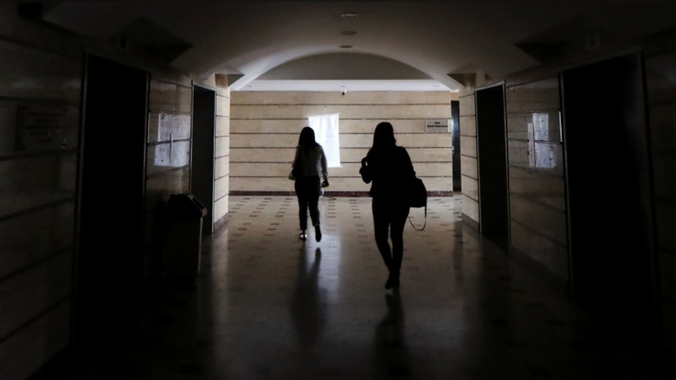 Dos mujeres caminan por un pasillo a oscuras en Caracas.