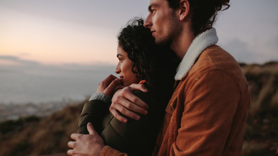 Una pareja abrazada contemplando el horizonte