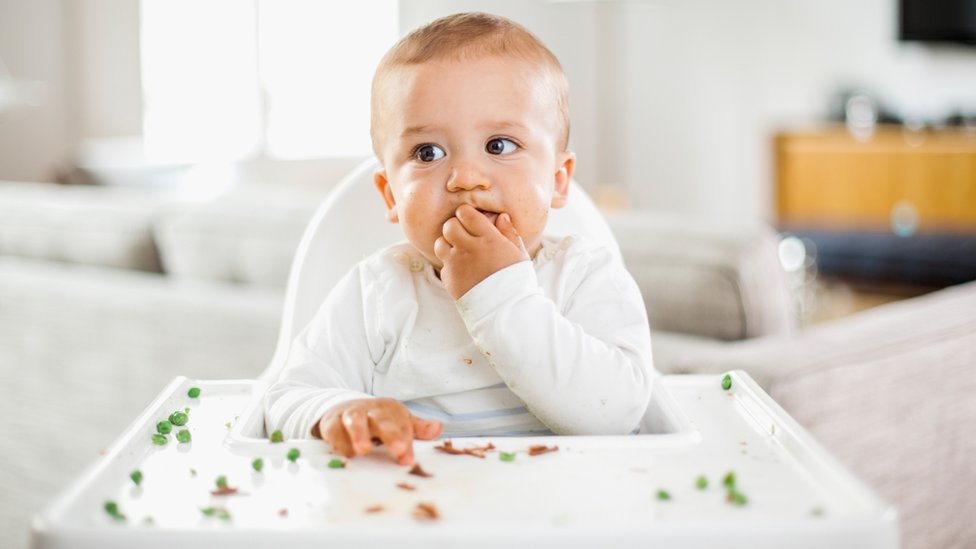 Типичное изображение ребенка, который ест со стульчика