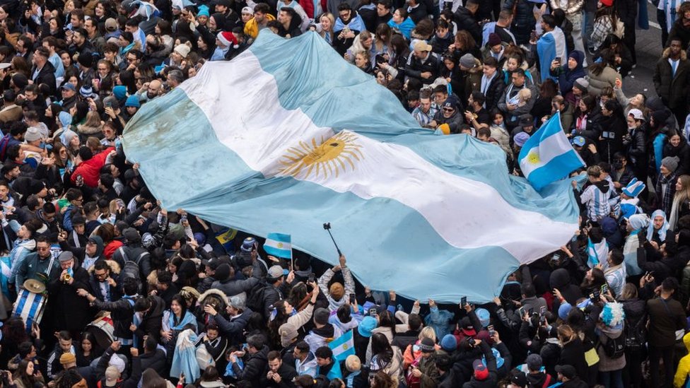 Gente portando una bandera de Argentina gigante.