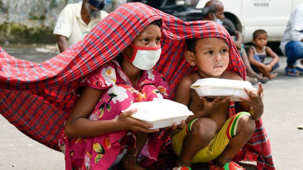 Two Bangladeshi children hold food parcels given away during the country's most recent lockdown