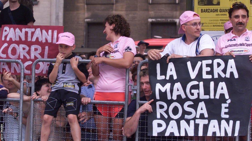 Italian fans behind a barrier, one carrying a sign claiming that 'Pantani is the true maglia rosa' (pink jersey)
