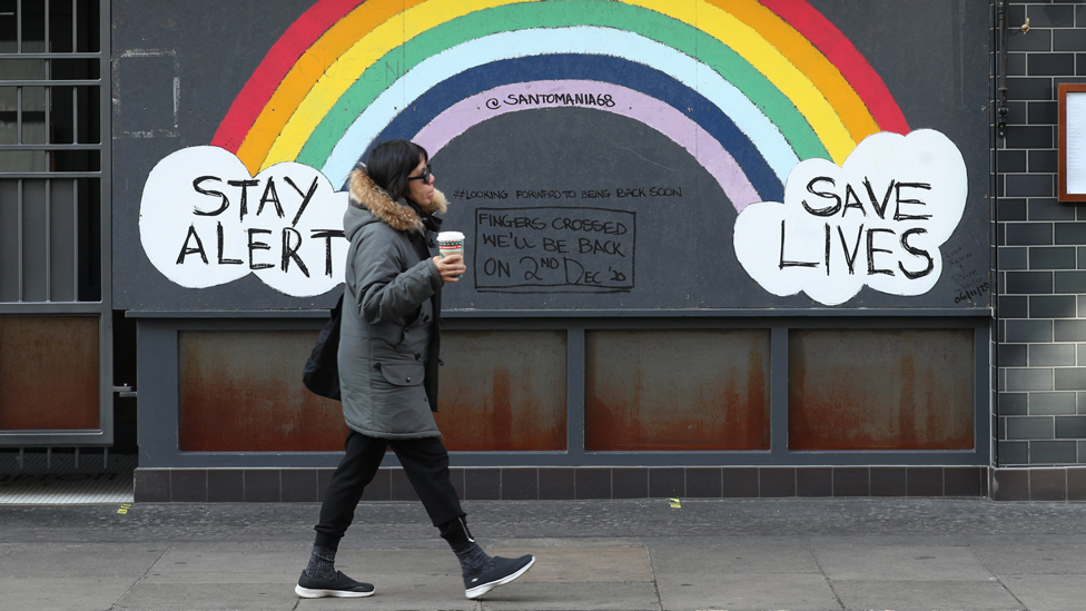 Person walking in front of a rainbow mural