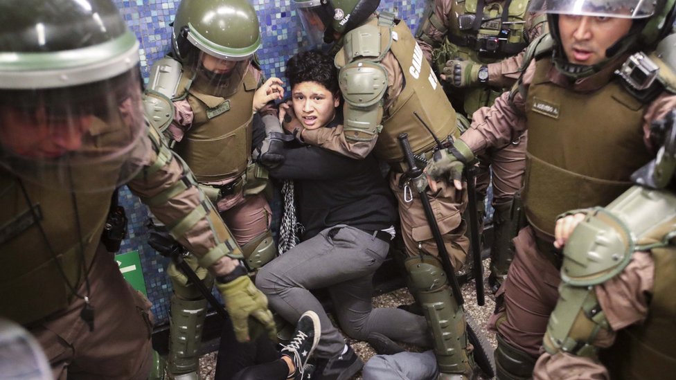 Чилийская полиция задерживает протестующего на станции метро Los Heroes в разгар демонстрации в Сантьяго