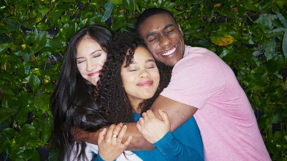 A man and two women embrace