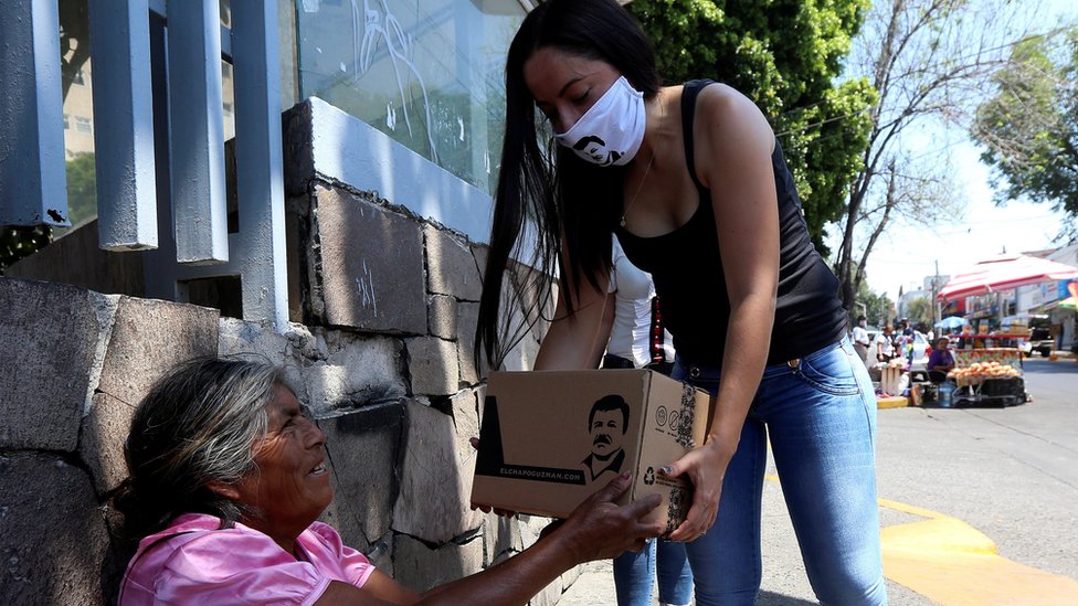 Женщина раздает продуктовые посылки от имени компании по производству одежды, принадлежащей дочери Эль Чапо Гусмана