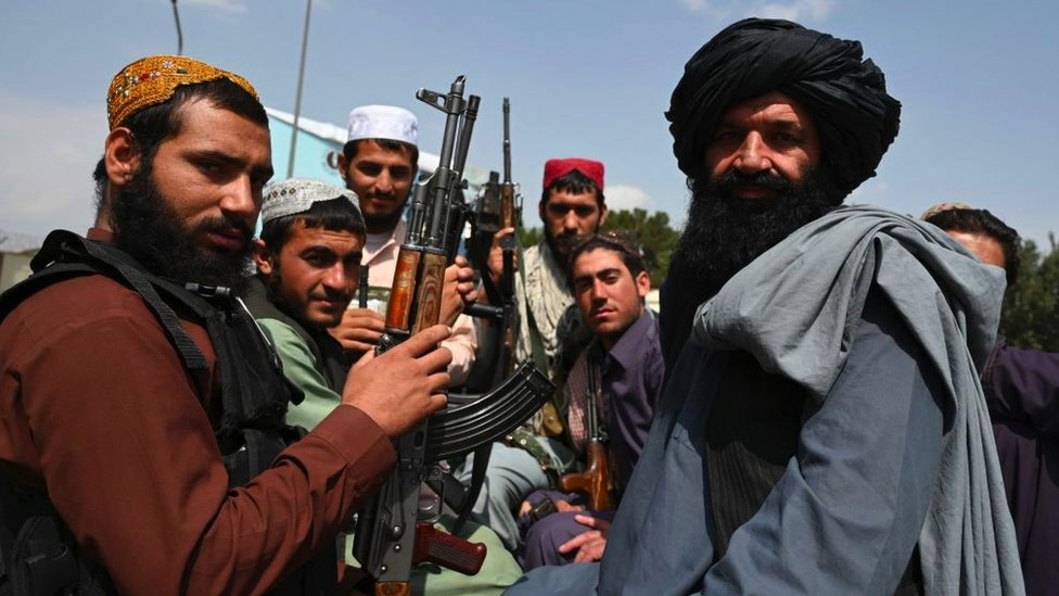 Militantes talibanes con armas en la parte trasera de una camioneta.