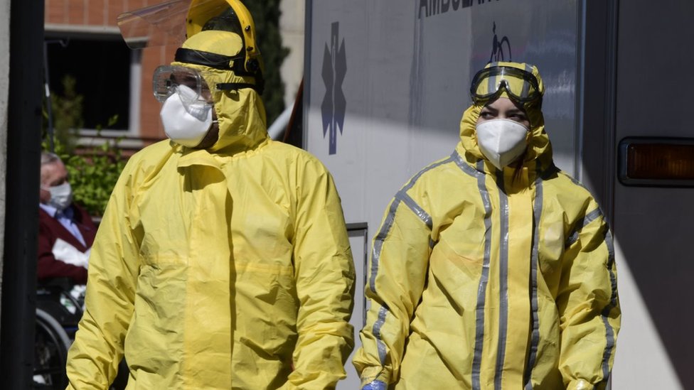 Медицинские работники в защитных костюмах стоят у входа в больницу Северо-Очоа в Леганесе, недалеко от Мадрида, 3 апреля 2020 г.