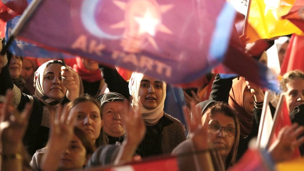 Supporters wave flags and banners as Turkish President and presidential candidate Recep Tayyip Erdogan makes an address