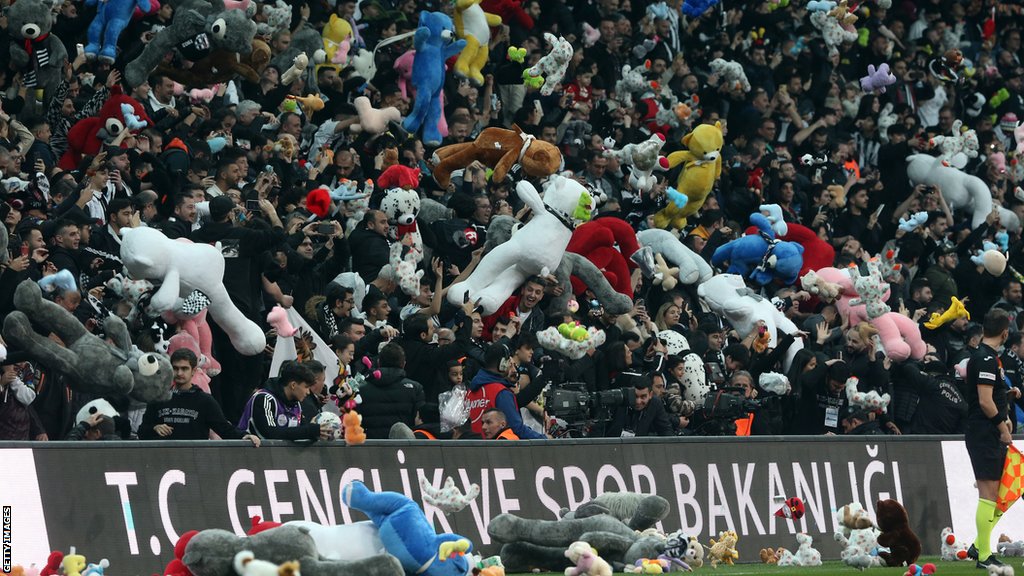 Fans of Besiktas throw Teddy bears onto the field in support for the earthquake victim children