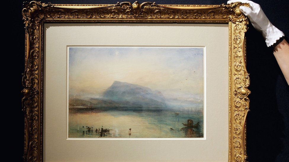 Сара Риз из Christies поправляет J.M.W. Акварель Тернера под названием «Голубой Риги: Люцернское озеро, восход солнца» на аукционе Christies