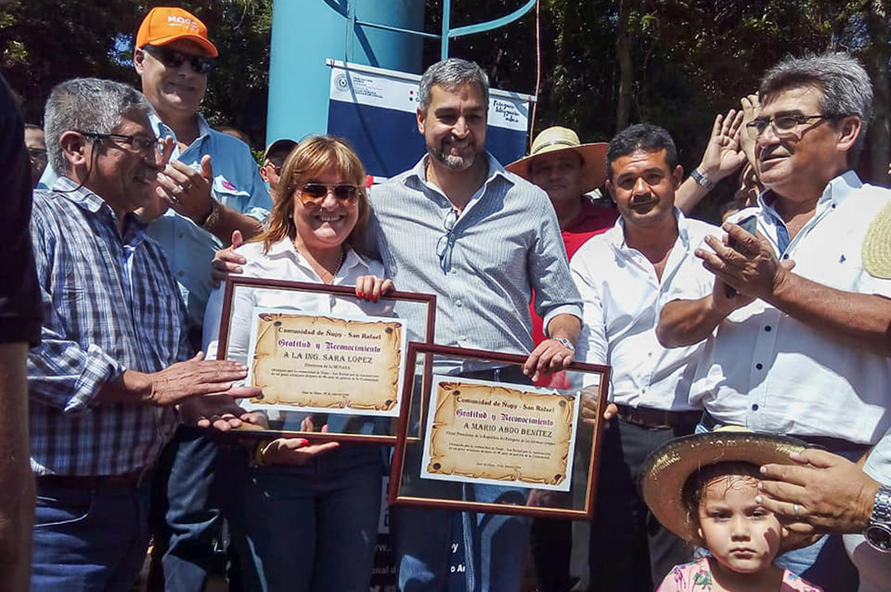 Sara López, directora general del Senasa, y el presidente paraguayo Mario Abdo Benítez reciben un reconocimiento de la comunidad Ñupy San Rafael, tras inaugurar un nuevo pozo de agua.