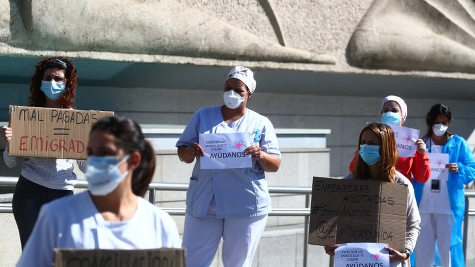 Медсестры держат плакаты во время акции протеста с требованием улучшения условий труда за пределами больницы Ла-Паса на фоне вспышки коронавирусной болезни