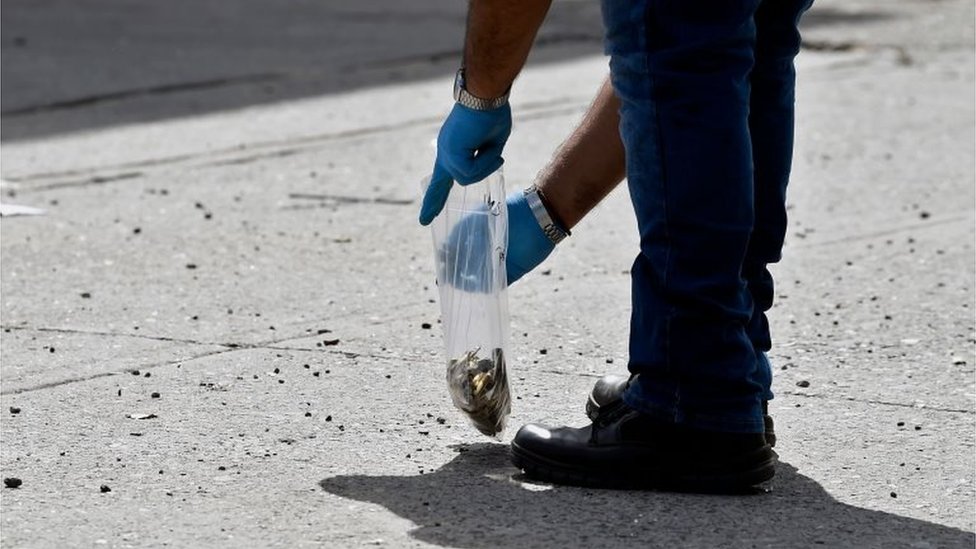 Сотрудник судебно-медицинской экспертизы собирает доказательства в мексиканском городе Кулиакан на следующий день после того, как члены картеля устроили буйство, 18 октября 2019 г.
