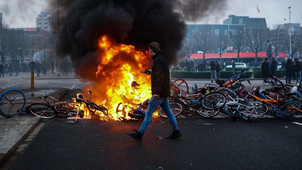 Protesters lay bikes down to block a street and set a fire during a protest against the coronavirus (Covid-19) measures, near Eindhoven Central Station, in Eindhoven