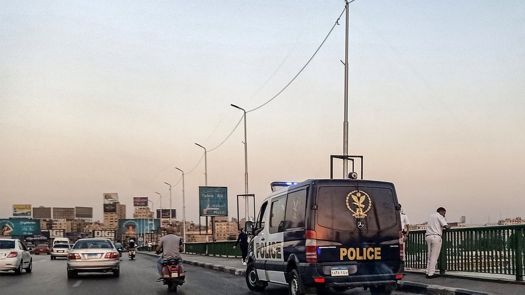 سيارة شرطة يقف إلى جانبها عناصر شرطة فوق جسر في مصر