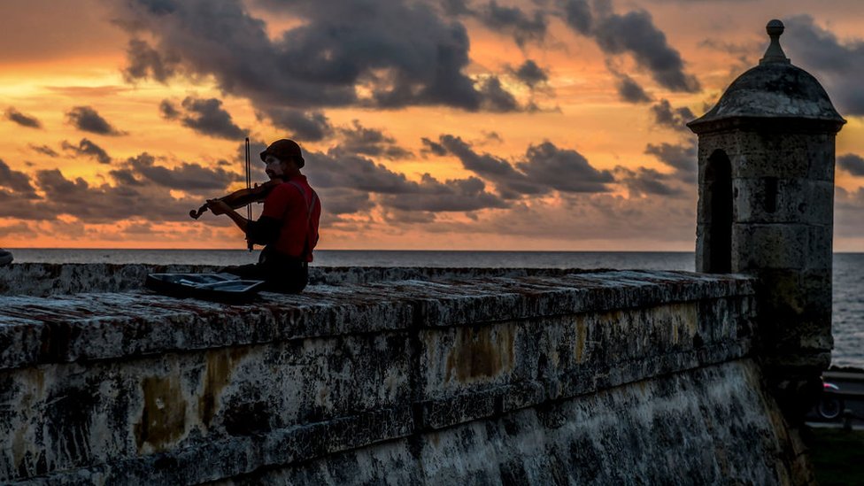 Un hombre disfrazado de payaso toca el violín en Cartagena de Indias