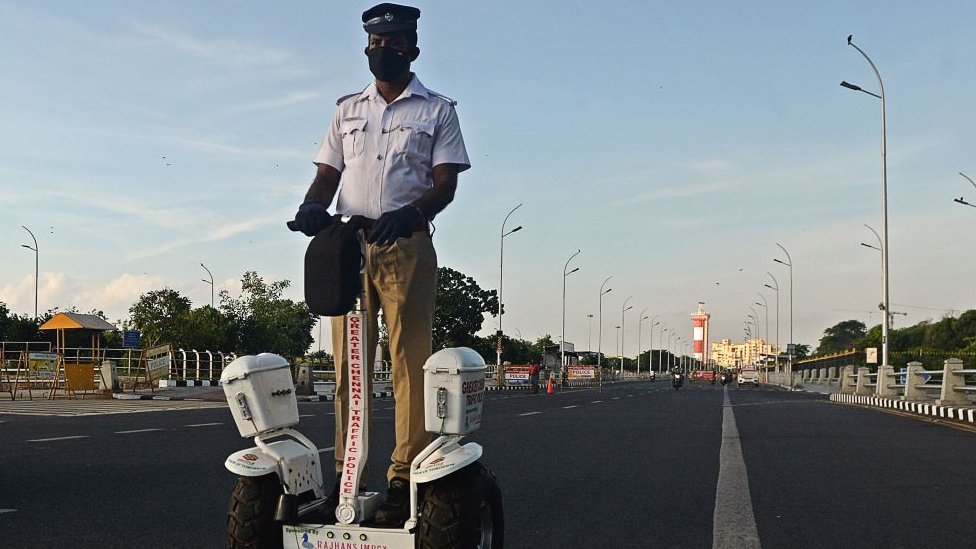 Сотрудник дорожной полиции едет на самобалансирующемся самокате во время блокировки в Ченнаи 15 мая 2020 г.