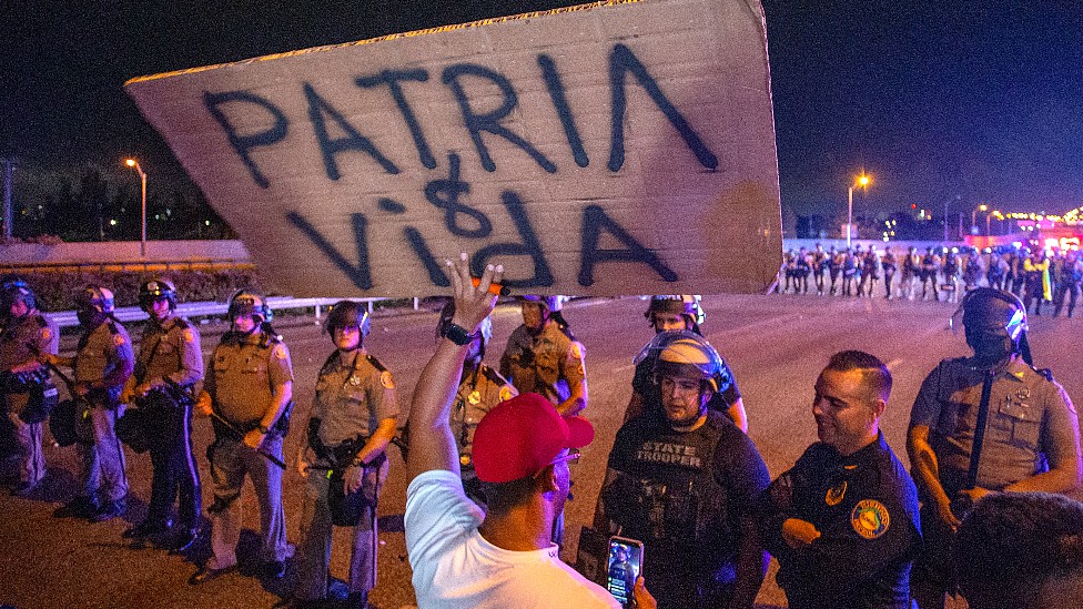 Un manifestante con un cartel en el que se lee Patria y Vida frente a una fila de policías