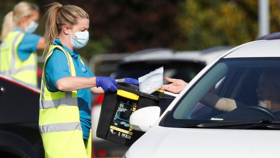 A driver drops a test for a coronavirus into a box in Bolton