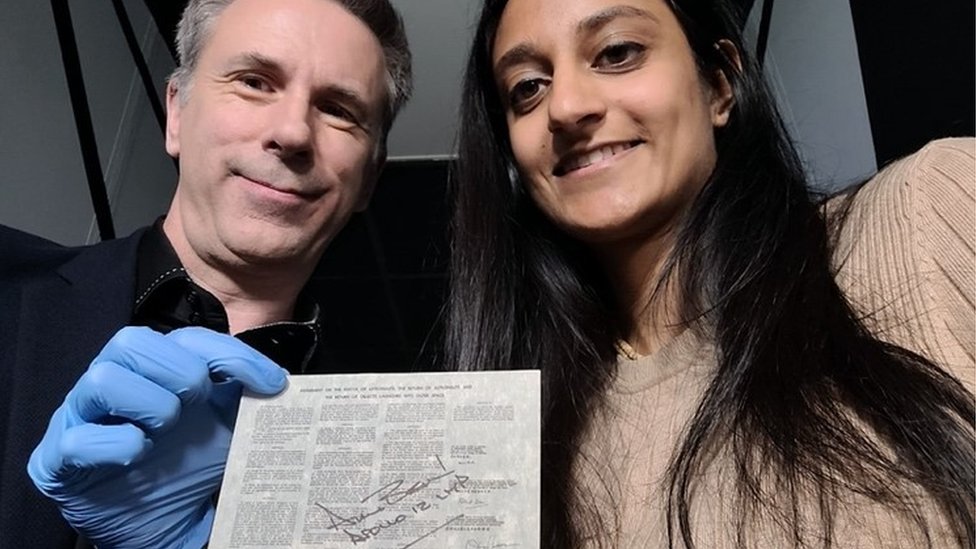 Spencer and Dhara pose with a document that's been to the moon.