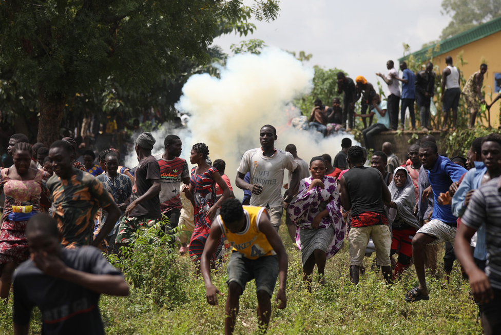 أشخاص يفرون من الغاز المسيل للدموع الذي أطلقته الشرطة أثناء عملية نهب جماعي لمستودع في أبوجا في نيجيريا. النهب طال مخازن حكومية تحوي مساعدات لمواجهة فيروس كورونا. ولا تزال الاضطرابات مستمرة في نيجيريا عقب احتجاجات ضدّ وحشية الشرطة اندلعت في أكتوبر/ تشرين الأول.