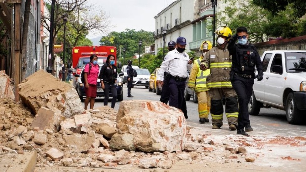 Сотрудники полиции и пожарной охраны наблюдают за ущербом, нанесенным обрушившейся стеной забора в Оахаке, Мексика, 23 июня 2020 года.