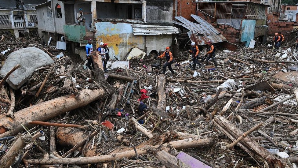 Pessoas caminhando e trabalhando sobre destroços