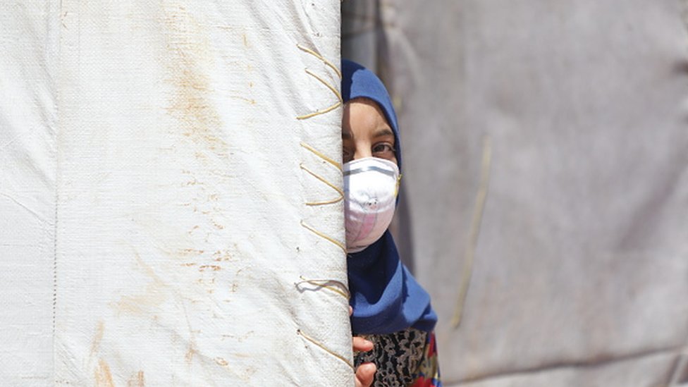 Сирийская девушка в медицинской маске в качестве меры предосторожности от коронавируса замечена в лагере беженцев в Идлибе