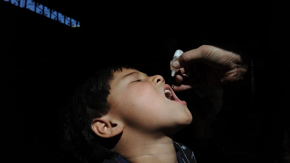 An Afghan health worker administers polio vaccine to a child on the first day of a vaccination campaign in Kabul on October 3, 201