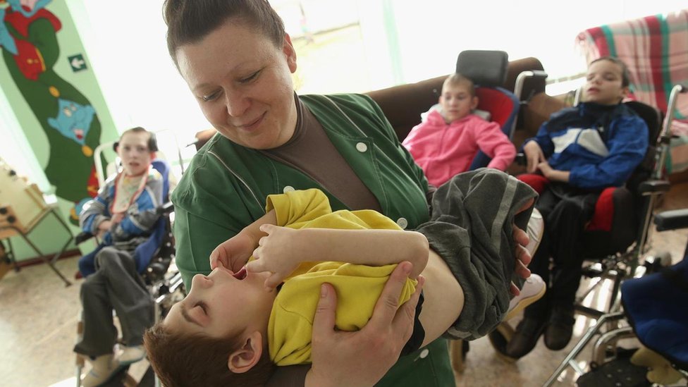 Una mujer sostiene a un niño con problemas motrices.