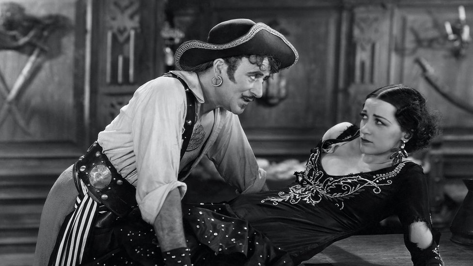 Кадр из пиратского фильма 1920-х годов, на котором пират-мужчина угрожает женщине