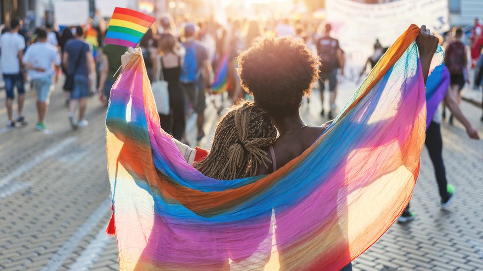 Two women wrapped in a rainbow flag