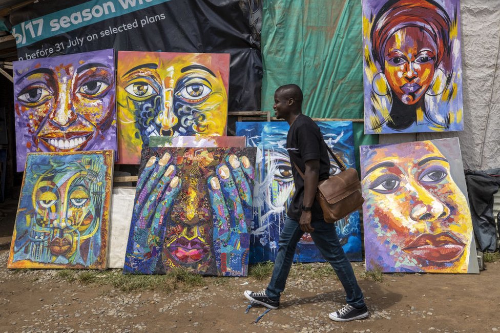 رجل يمشي أمام لوحات معروضة للبيع على جانب الطريق في العاصمة النيجيرية أبوجا يوم الاثنين.