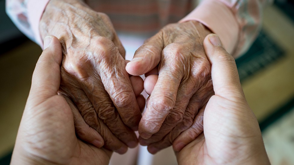 Manos de una persona mayor en las manos de una cuidadora
