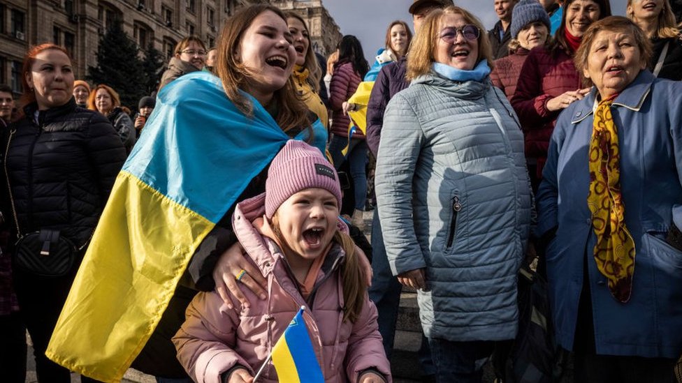 Personas cantan en Kyiv festejando el triunfo en Jersón.