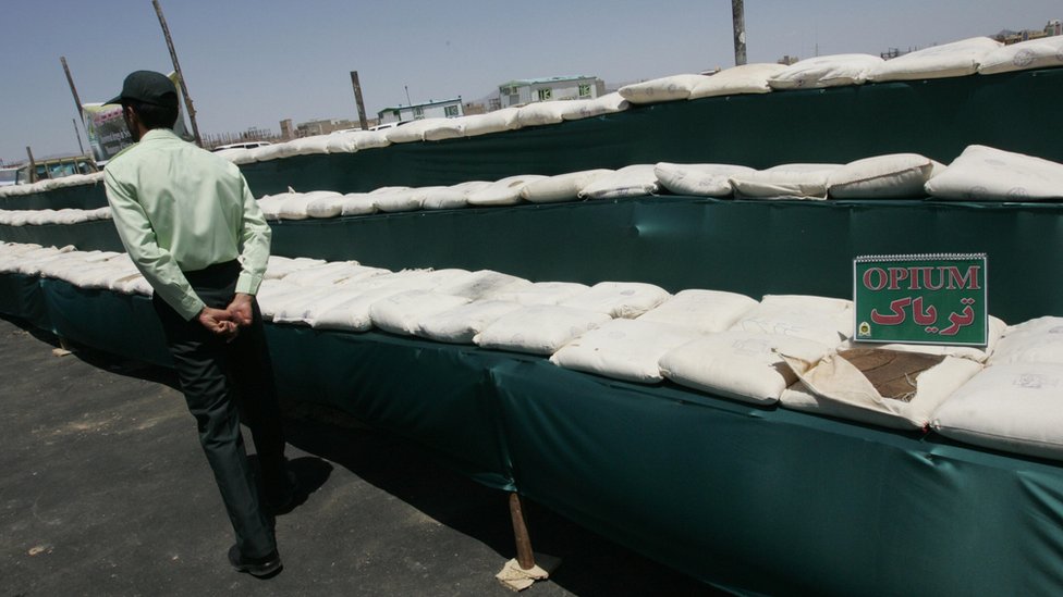 На снимке изображен иранский полицейский, охраняющий 3000 кг (6600 фунтов) опия, изъятого у контрабандистов наркотиков.