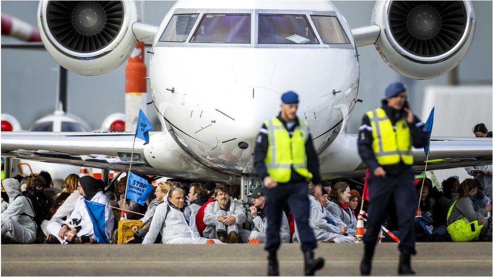متظاهرون يجلسون تحت طائرة خاصة في مطار سخيبول في 5 نوفمبر/ تشرين الثاني
