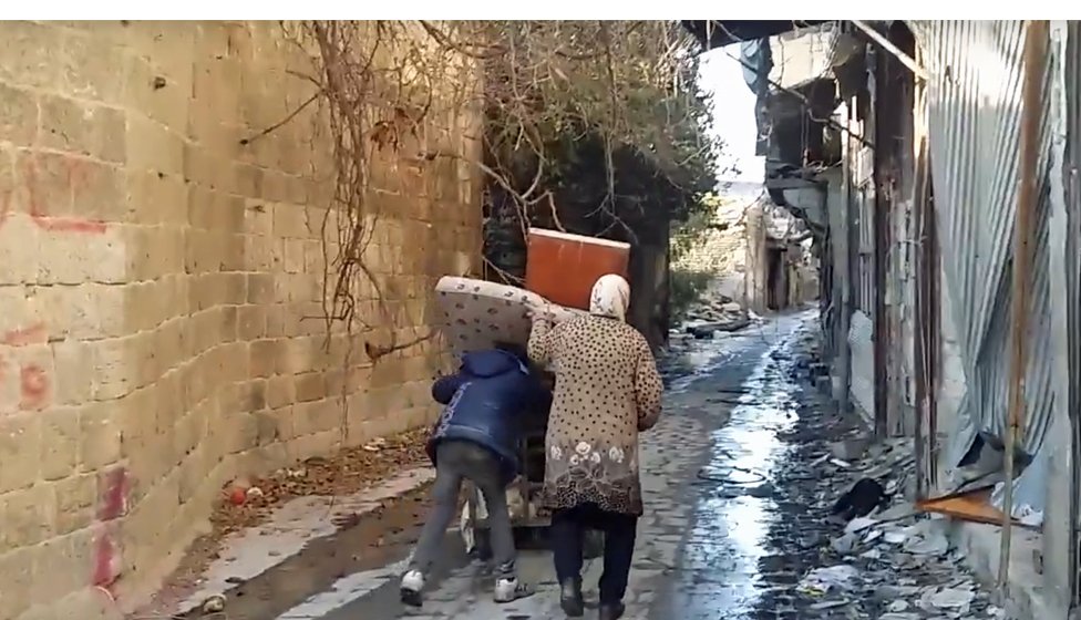 Las personas retornaban a sus casas para salvar algo de sus pertenencias. Personas con pertenencias en las calles de Judaydah.