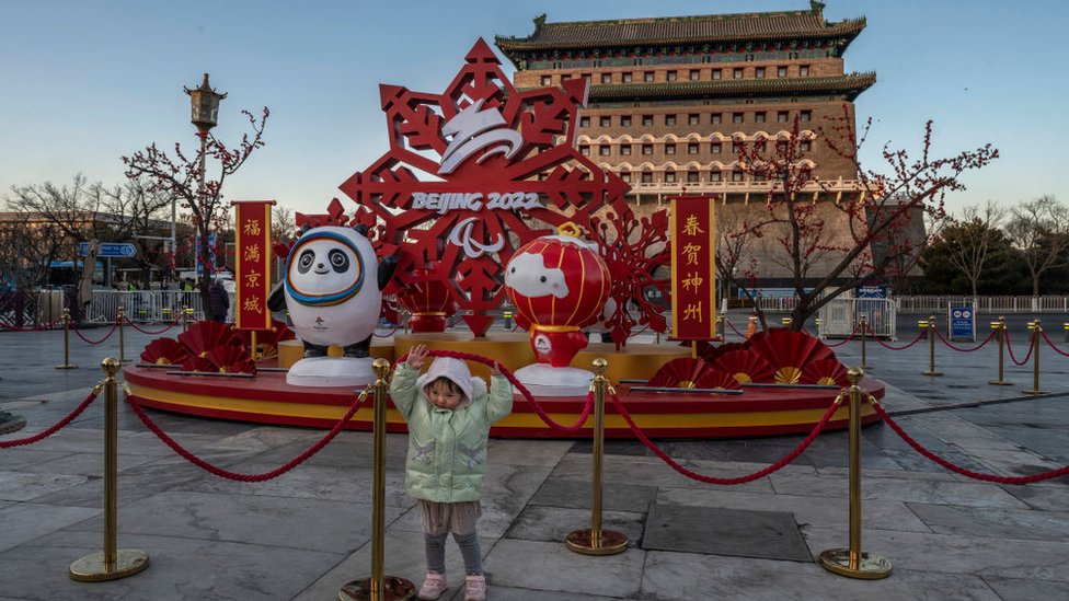 Una niña posa frente a un escenario decorativo de los Juegos en el centro de Pekín