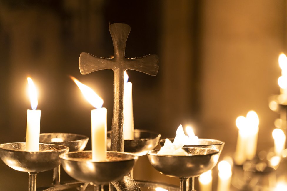 Una cruz rodeada de velas encendidas en una Iglesia.