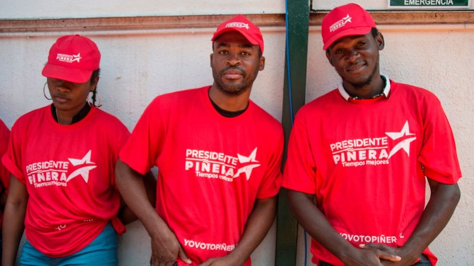 Inmigrantes haitianos con camisetas de apoyo a Piñera en la campaña electoral.