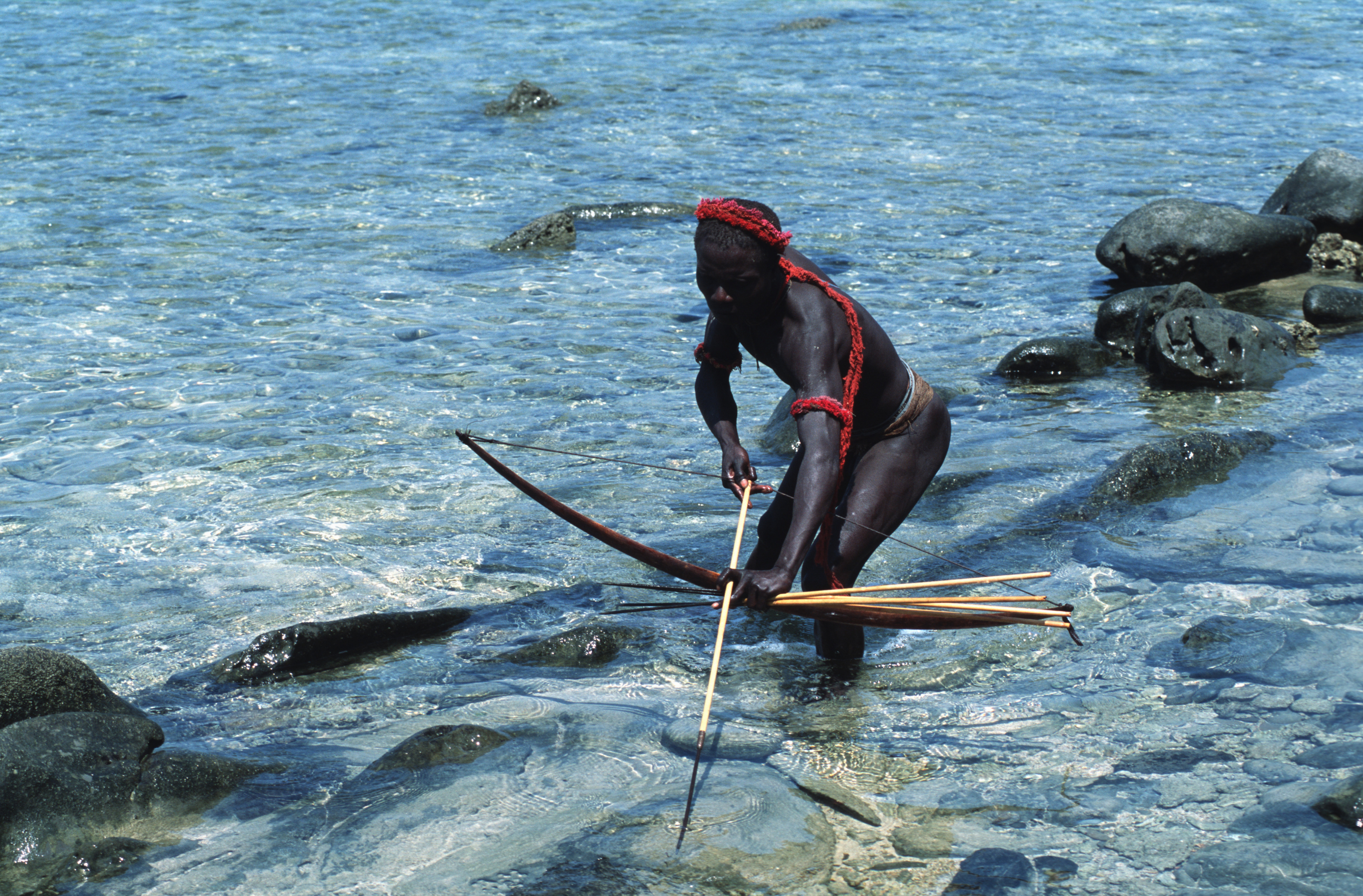 A Jarawa man catching fish with bow and arrow