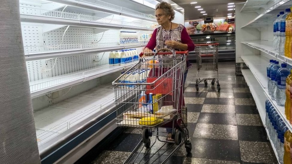 Seorang penduduk Venezuela berbelanja di sebuah toko serba ada yang nyaris kosong barang di Caracas.