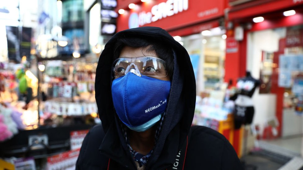 Мужчина в маске для предотвращения коронавируса (COVID-19) гуляет по торговому району Мёндон 23 февраля 2020 года