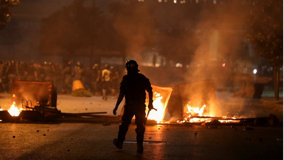 Офицер ОМОНа идет к горящему костру во время протестов в Бейруте