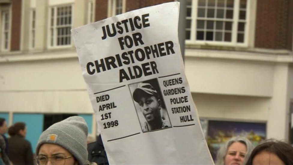 Люди держат плакат с надписью: «Справедливость для Кристофера Олдера»