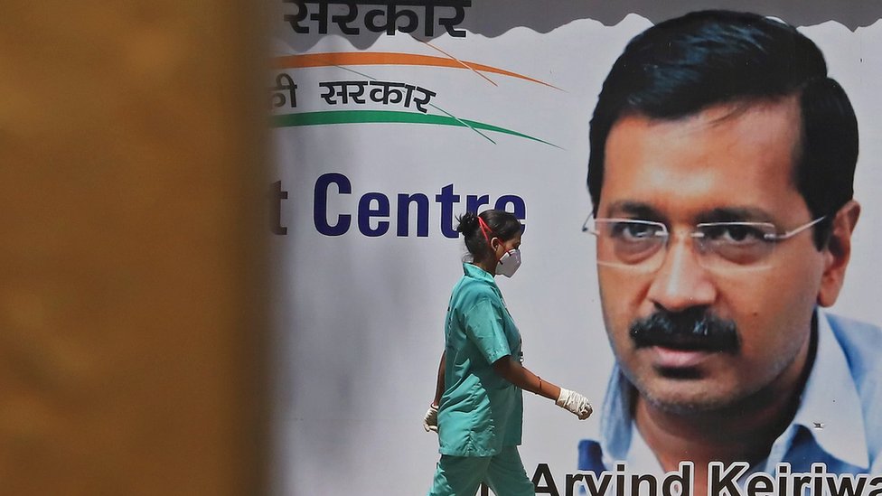 A health worker walks past a billboard for Arvind Kerhiwal in 2021