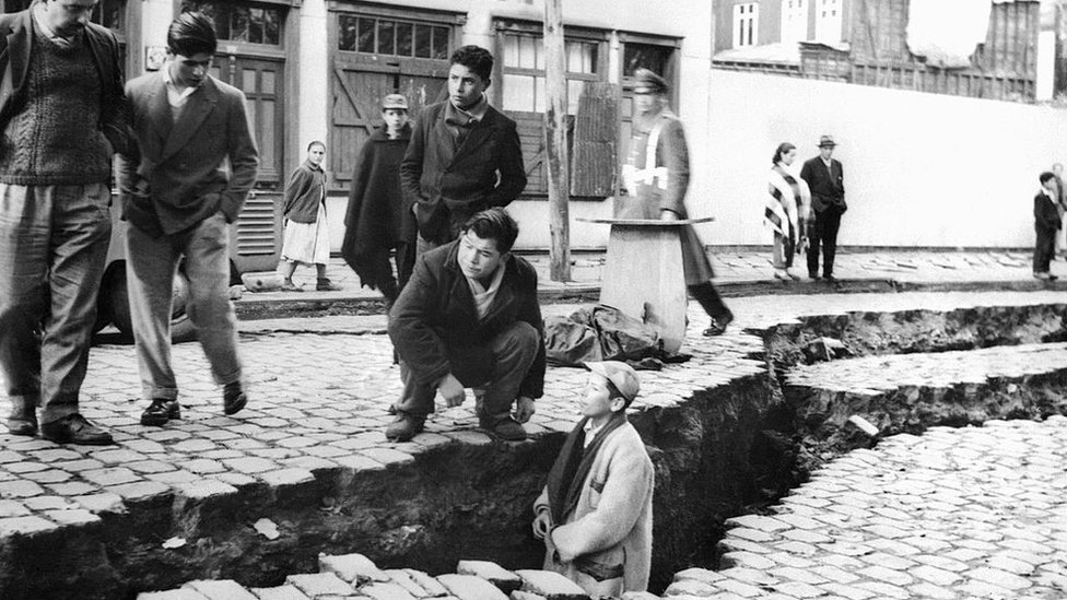 Un joven en una de las grietas en la calle producto del terremoto en Valdivia, Chile, en 1960.