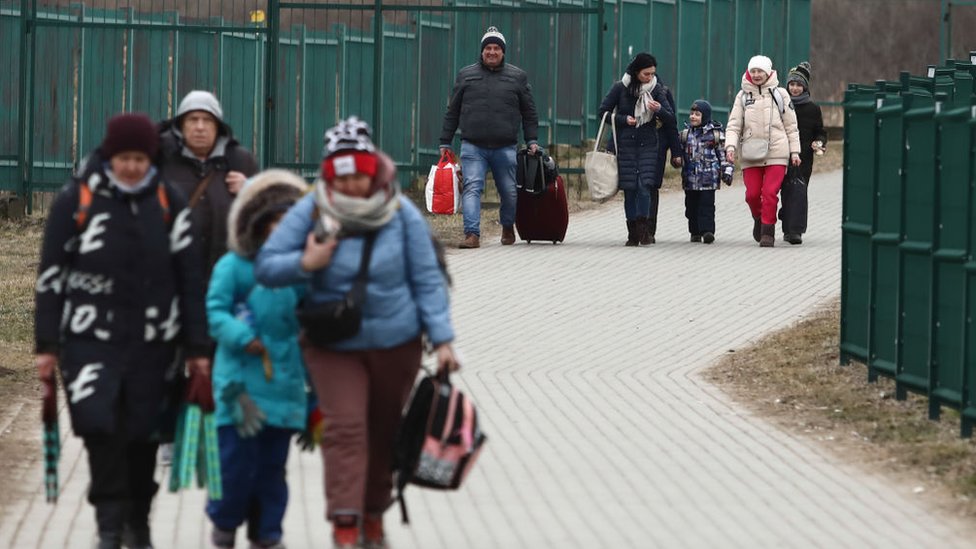 لاجئون من أوكرانيا يمشون بعد عبورهم الحدود إلى بولندا